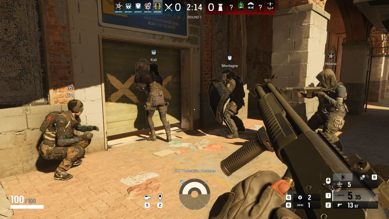 A first-person Siege view shows teammates gathered outside a barricaded doorway.