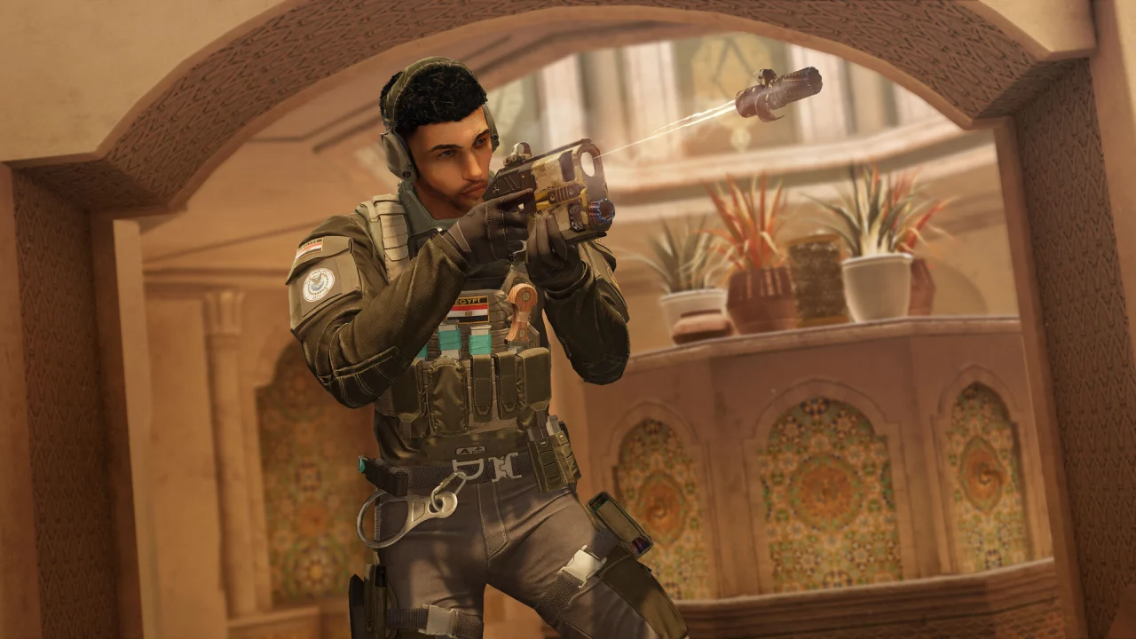 A dark-haired Siege operator aims a suppressed rifle beneath a carved stone arch.